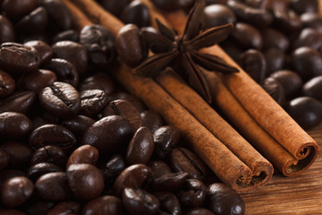 Coffee beans with cinnamon and anise on wooden table