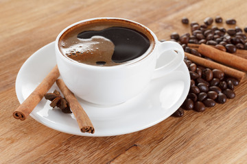 Coffee cup and beans, cinnamon sticks, anise on wooden table