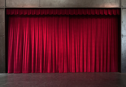 Photograph of a red theater curtain behind an empty stage.