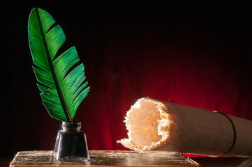 Green quill pen and a rolled papyrus sheet