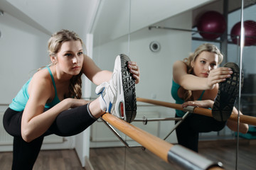 Woman doing stretching near barre in fitness center
