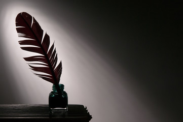 Silhouette of a quill pen and inkwell against a beam of light