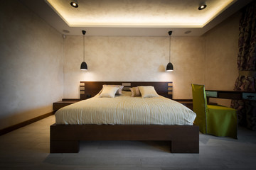 Double bed in brown colored modern bedroom interior