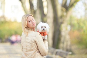 Portrait of a beautiful young woman carrying her cute little Maltese dog