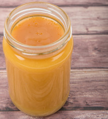 Orange fruit curd in a jar over wooden background