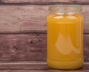 Orange fruit curd in a jar over wooden background