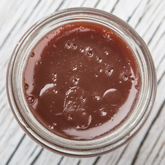Raspberry fruit curd in glass jar over wooden background