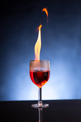 wine glass with burning alcohol on black background