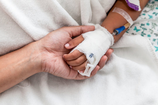 mother holding child's hand who have IV solution in the hospital