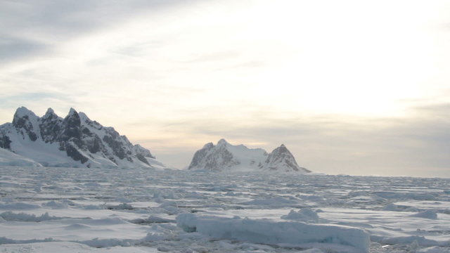 Traveling through ice field towards entrance to Lemaire Channel, Antarctica at twilight in summer.
