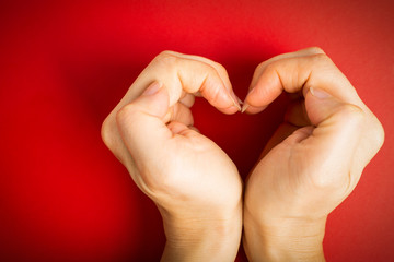 Female hand posing Love shape in red background