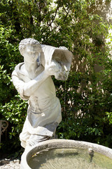 Ancient sculpture of a man with a bucket of water in Boboli Gardens, Florence, Italy