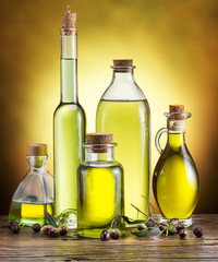 Glass bottles of olive oil and few berries on the wooden table.