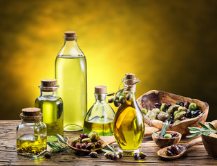 Glass bottles of olive oil and few berries on the wooden table.