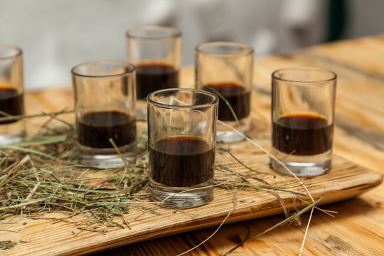 glass stack with alcohol are on a wooden tray with hay