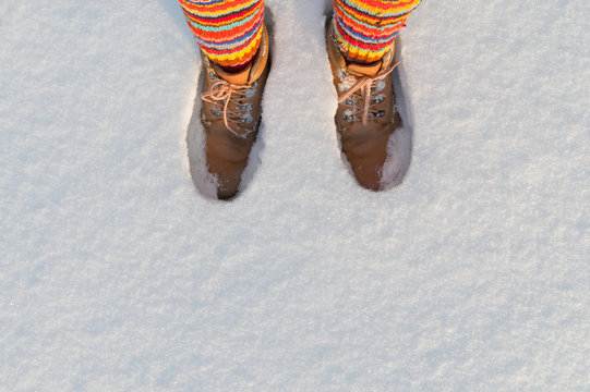 Feet with warm colorful striped wool socks in snow.