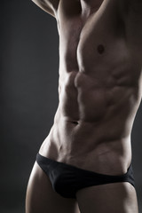 Fototapeta premium Handsome muscular bodybuilder posing on gray background. Low key close up studio shot