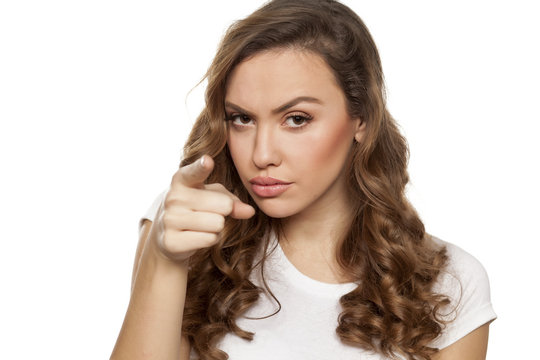 angry beautiful girl pointing a finger at you on a white background