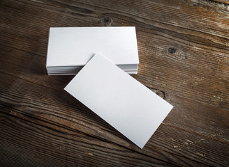 Blank white business cards on a dark wooden background. Mockup for branding identity. Blank...