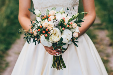 mariée tenant un bouquet de fleurs dans un style rustique, bouquet de mariage
