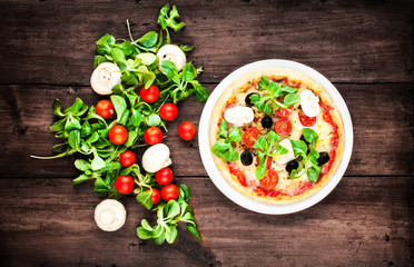 Pizza with fresh vegetables over rustic wooden table top view cl