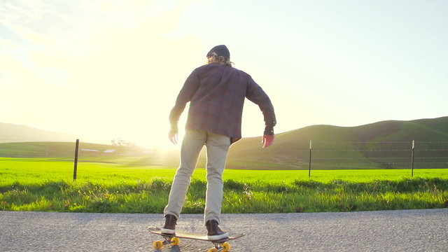 Slow Motion Skateboarder Riding Down Hill At Sunset 