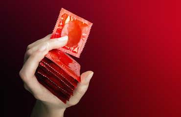 Woman's hand with seven  red  condoms