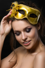 Portrait of young beautiful woman wearing golden party mask