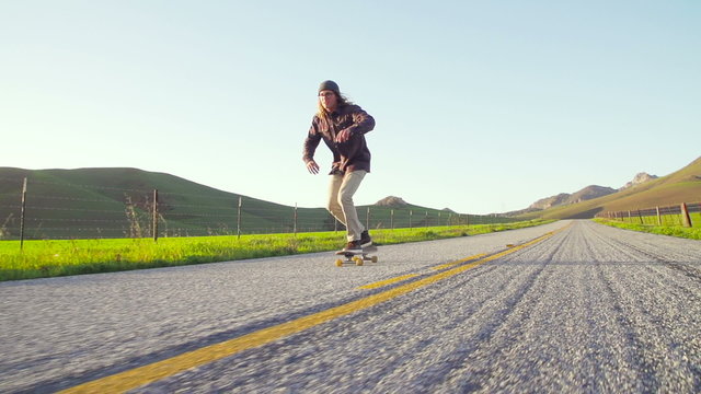 Slow Motion Man Skating Down Country Road At Sunset 