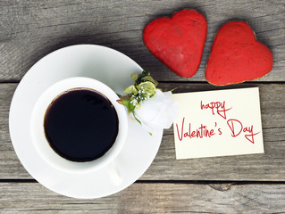 Romantic breakfast on Valentine's Day. Cup of coffee and heart shape cookies, white rose decoration, Happy Valentine's Day message. Toned image
