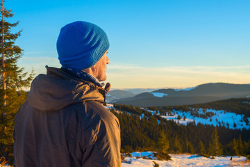 Fototapeta na wymiar Hiker man standing in winter mountains looking into the distance