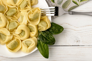 Tortelloni with spinach and ricotta on wooden table.