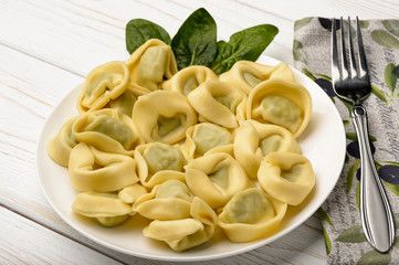 Tortelloni with spinach and ricotta on wooden table.