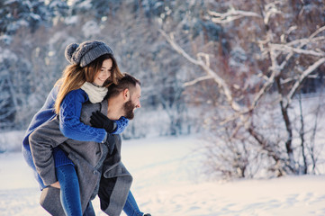 happy loving couple walking in snowy winter forest, spending christmas vacation together. Outdoor seasonal activities. Lifestyle capture.
