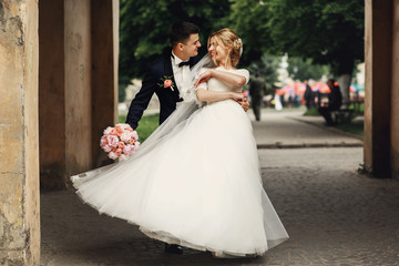 Fototapeta na wymiar Happy handsome groom and blonde beautiful bride in white dress d