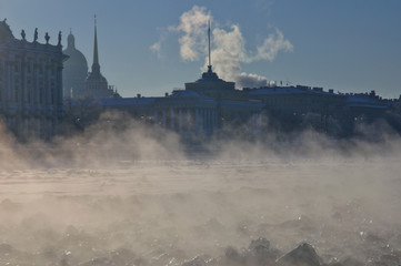 Very cold winter day in the city center of St. Petersburg. View of St. Isaac Cathedral and Admiralty building through the steam rising over ice channel to navigate the frozen Neva river. - 101034680