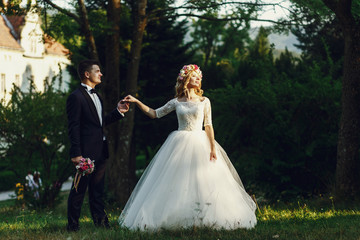 Obraz na płótnie Canvas Gorgeous blonde young bride and charming groom holding hands at