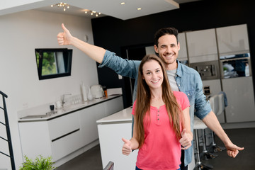 Fototapeta na wymiar cheerful young couple happy in their new modern design house showing thumbs up