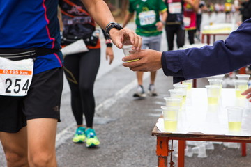 Hand give Minerals water to Unidentified runners catching up Minerals water