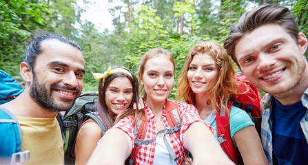 friends with backpack taking selfie in wood