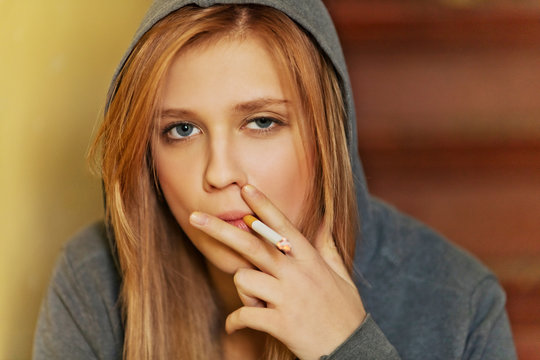 Teenage woman sitting on stairscase and smoking cigarette