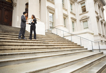 Two well dressed professionals in discussion on the exterior steps of a building. Could be lawyers,...