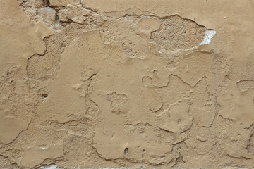 Old ochre painted stucco wall with cracked plaster. Background t