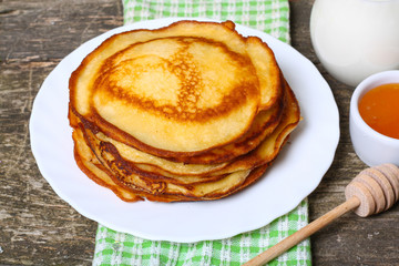 sweet pancakes with honey on wooden background 