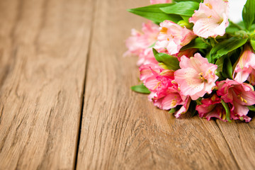 Fototapeta na wymiar bouquet of pink alstroemeria on wooden plate
