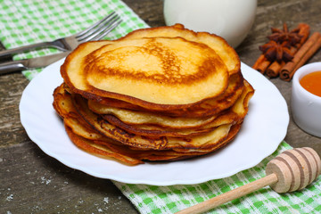 sweet pancakes with honey on wooden background 