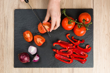 Top down view on cutting board with hands slicing vegetables