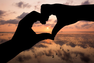 Silhouette hand in heart shape with sunrise