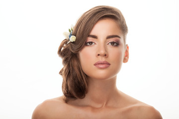 Fototapeta premium Closeup studio portrait of young elegant brunette woman with adorable makeup low bun hairstyle flower headpiece white background