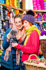Junge Frauen kaufen Wolle und Garn für ihr Hobby in einem Laden oder Fachgeschäft für Handarbeit, Kurzwaren und Strickgarn